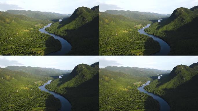 沿河的筏屋的绿色自然鸟瞰图，在热带绿色森林和宁静的河流上飞翔，早晨的阳光