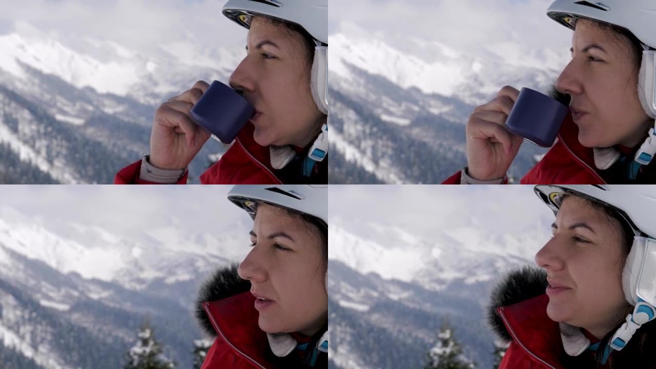 戴防护头盔的女滑雪者在滑雪场喝热茶咖啡