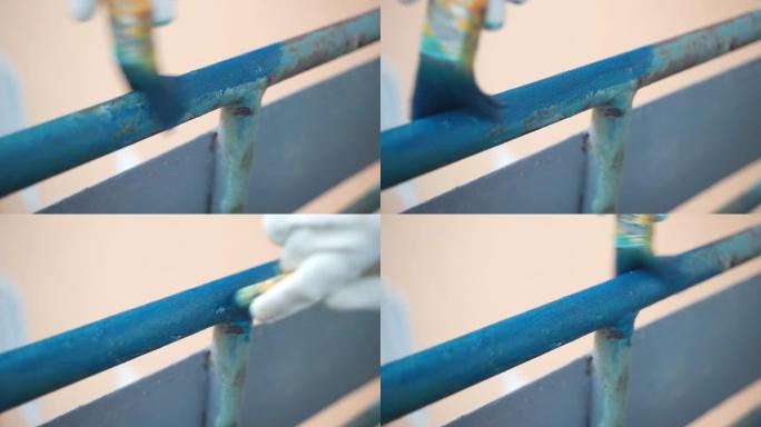 人画铁制阳台栏杆用亮蓝色，人覆盖金属表面后生锈和腐蚀去除。铁施工修复和刷新过程，旧腐蚀铁表面的绘画