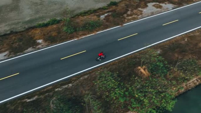 骑自行车公路旅行与女运动员骑手在早上的无人机视图