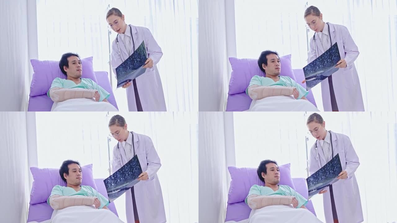 高加索女医生向在医院病床上听的亚洲男性患者解释脑部x光片。由专家医生护理。神经退行性疾病的诊断脑部血