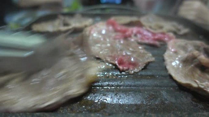 薄薄的新鲜瘦牛肉在煎锅上嘶嘶作响