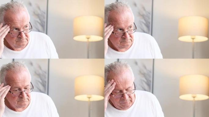 欧洲老年养老金领取者坐在家里的沙发上，头痛和沮丧。健康问题