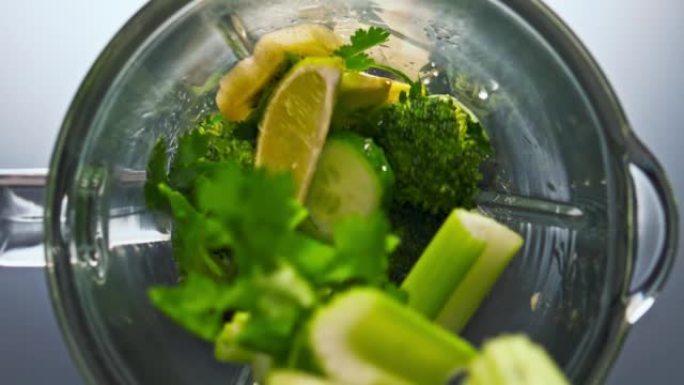 生绿色蔬菜坠落搅拌机在超慢动作特写。维生素食品。