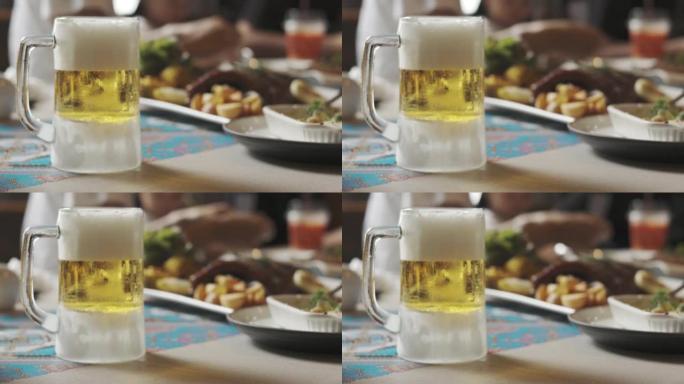 慢动作4k，餐桌上有美丽的金色和琥珀色啤酒磨砂玻璃的模糊背景，与家人或朋友共进晚餐或庆祝派对看起来清