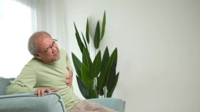患有胸痛的高级男性因心脏病发作而受苦。老人病人呼吸困难，他的胸部坐在家里的沙发上。医疗保险退休概念。