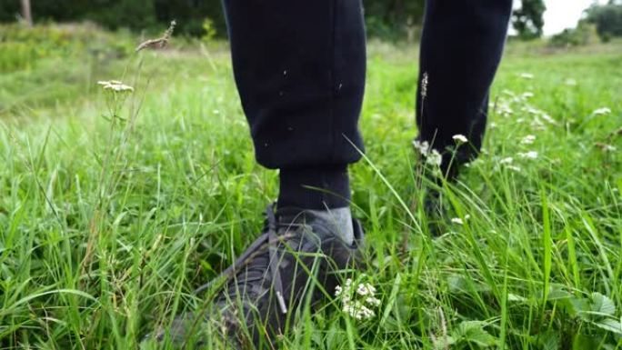 远足靴在草地上行走的特写镜头，慢动作。