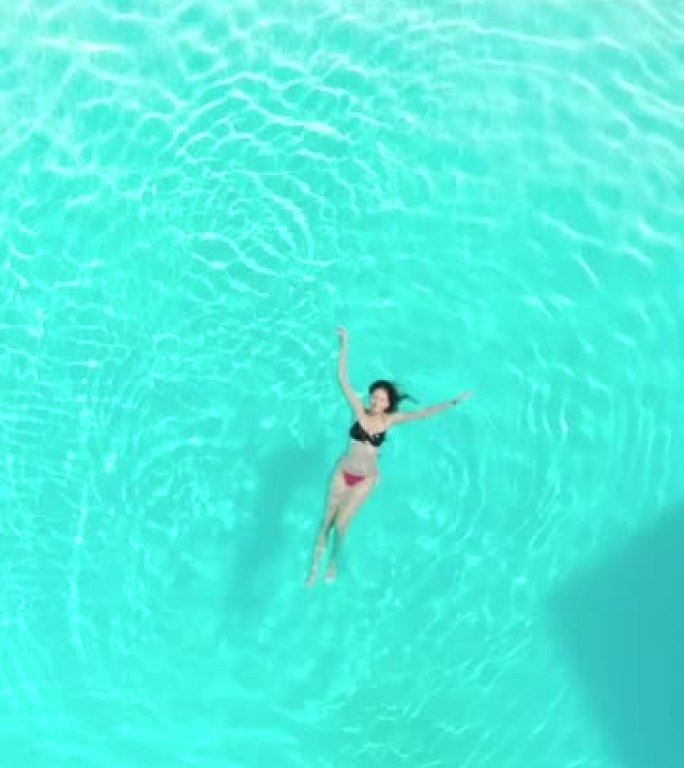 游泳池中穿着比基尼的美丽西班牙裔妇女的垂直镜头