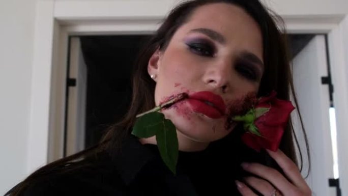 美丽的年轻黑发女人，万圣节化妆，嘴里有玫瑰花。