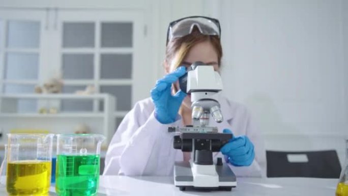 亚洲女性生物化学家使用显微镜在实验室，科学家医生与各种细菌，组织，抗生素的药物研究，看着相机和迷人的
