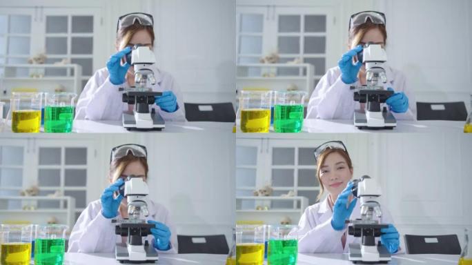 亚洲女性生物化学家使用显微镜在实验室，科学家医生与各种细菌，组织，抗生素的药物研究，看着相机和迷人的