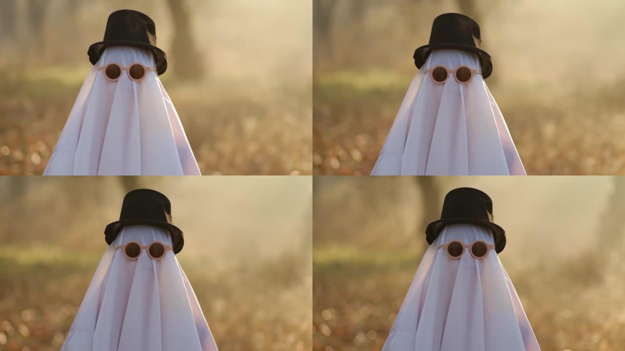 一个幽灵，上面覆盖着白色幽灵般的叶子，戴着帽子在森林里过万圣节。万圣节概念