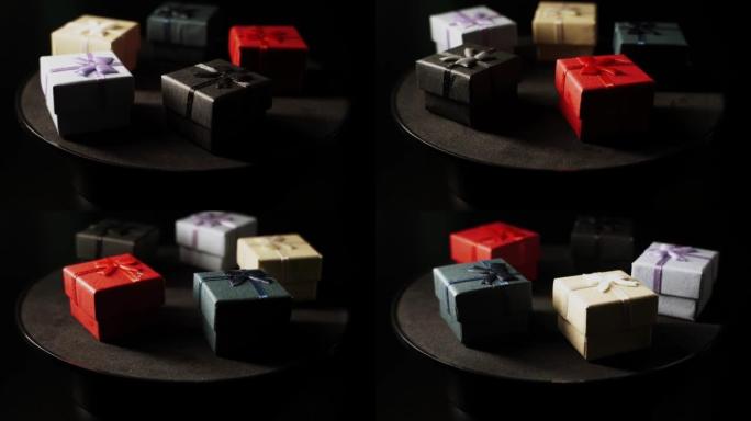 许多带有礼物的不同颜色的盒子在黑色背景上旋转。节日和生日的概念4k