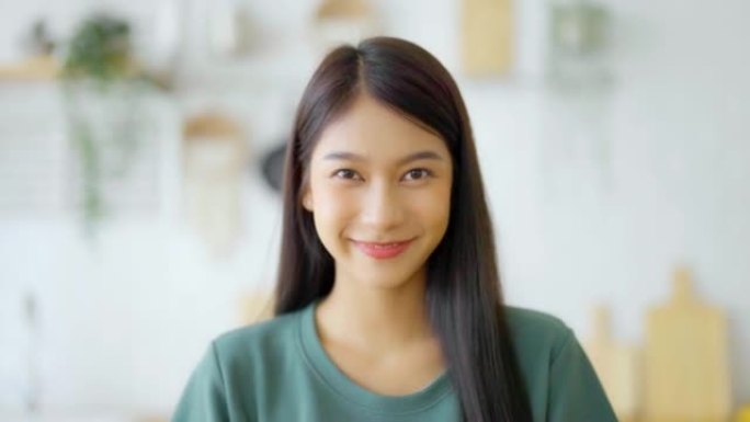 肖像微笑的亚洲年轻女子看着镜头。面部表情快乐