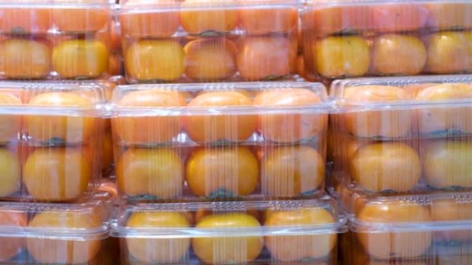 塑料容器中的成熟柿子在超市里特写镜头。