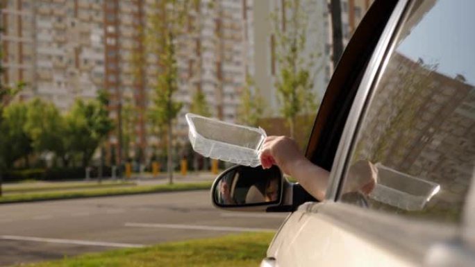 一个女人从车窗里扔塑料垃圾的特写镜头。