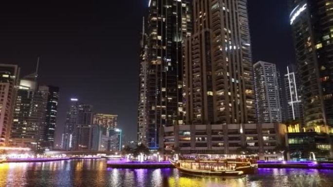 高质量的镜头一艘旅游船，在迪拜码头上航行的观光船。阿拉伯联合酋长国迪拜码头的夜间步行