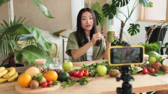 年轻的亚洲女性博客作者或内容创作者准备冰沙并在相机上录制视频