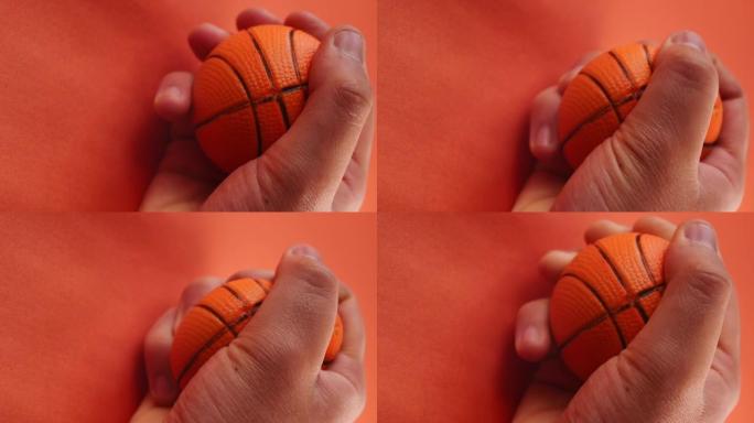 男人的手挤压一个橙色的小篮球球