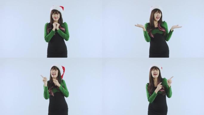 快乐的亚洲女人戴着圣诞老人的圣诞帽跳舞，并在白色背景工作室展示一些孤立的东西。新年快乐假期概念