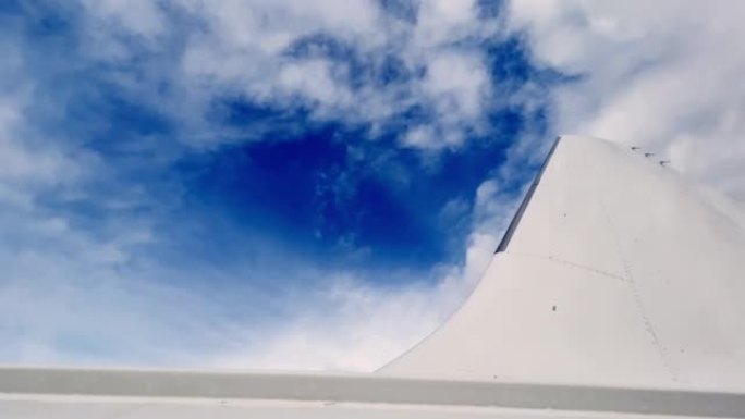 飞机尾部和白色机身表面的低角度平移视图。背景中的蓝天