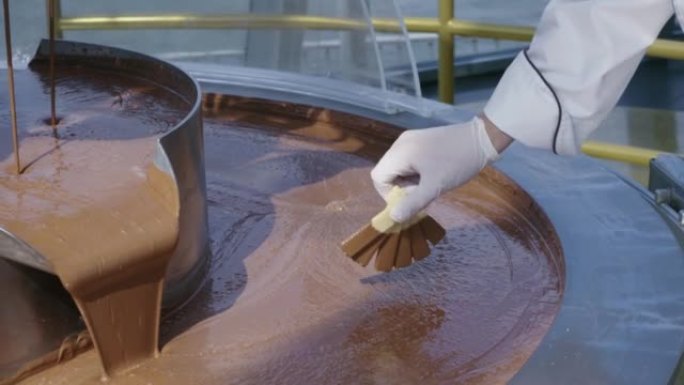 男人将威化饼测试器浸入融化的液体喷泉中，并带有美味的巧克力，慢动作