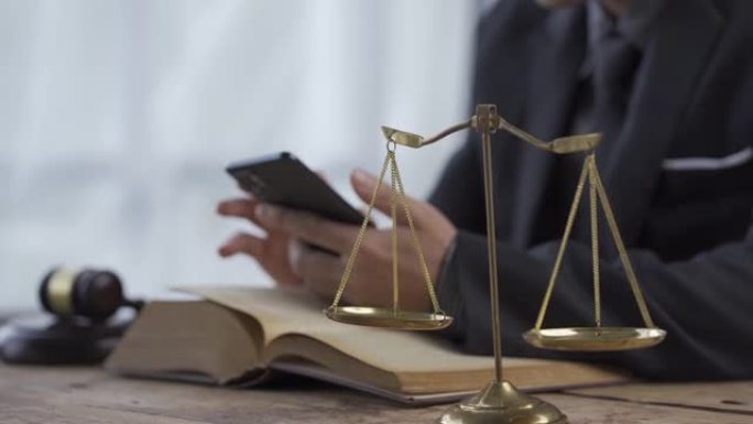 律师事务所的概念在线法律咨询和法律咨询。律师法官坐在桌上，拿着纸质智能手机和锤子司法4K