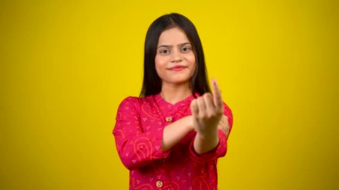 年轻的印度女孩在投票后伸出手指，开朗的女孩被隔离在黄色背景中