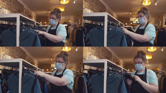 戴着安全面具的女店长在服装店做库存。实时
