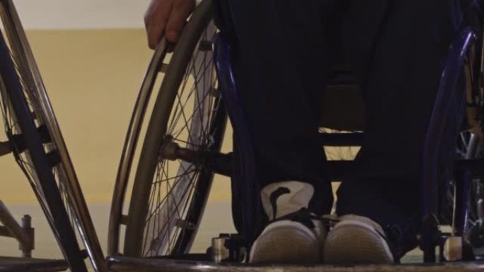 一个运动的残疾人坐在轮椅上在学校体育馆打篮球队的特写镜头。有选择性的重点。