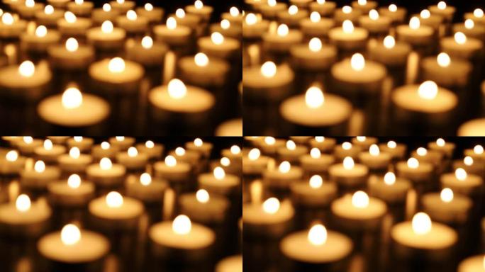 在黑暗的散焦中燃烧蜡烛。纪念死者的蜡烛