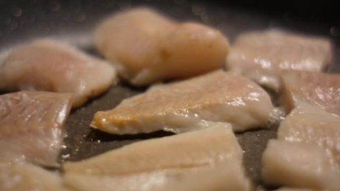 用油关闭煎锅的鱼片带鱼。烤健康食品。油炸鳕鱼片配香料特写。健康饮食欧米茄3。低热量白肉。