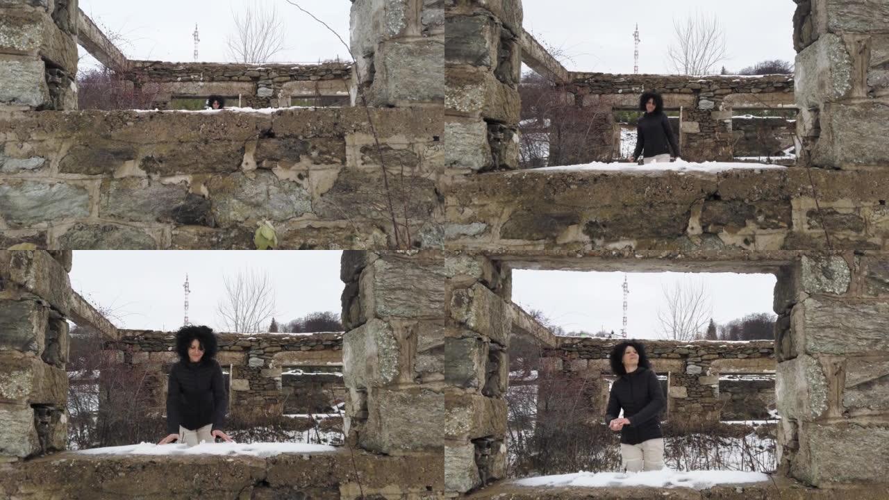 女人在一栋旧建筑的废墟中，墙上有洞被雪覆盖