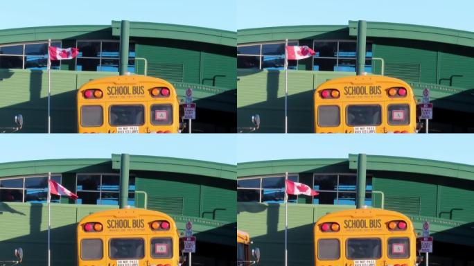 一辆黄色校车，飘扬着加拿大国旗，背景是一所学校。