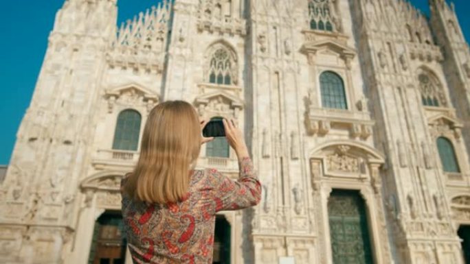 女人通过意大利地标性米兰大教堂的智能手机拍照或录像