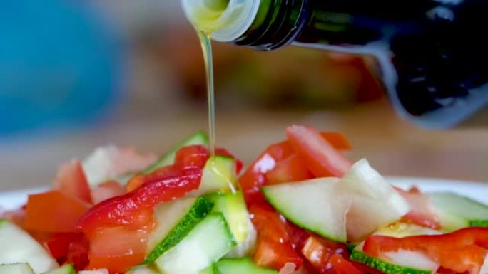 蔬菜新鲜沙拉食品健康餐地中海厨房素食橄榄油。特写镜头将橄榄油倒在新鲜沙拉上。关闭健康午餐，五颜六色的