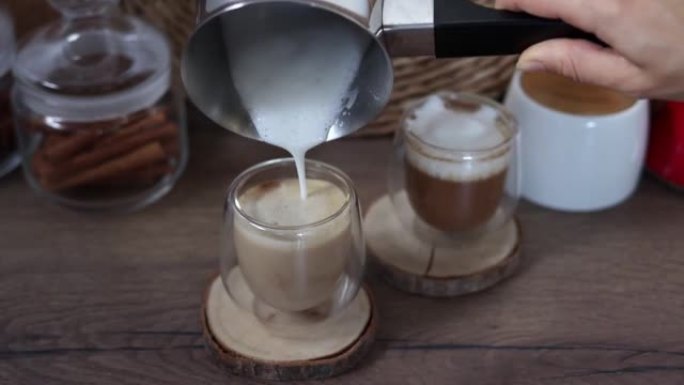 女人的手将土耳其人的泡沫牛奶倒入玻璃杯中的新鲜咖啡中。早餐咖啡概念。在家煮咖啡的过程。慢动作