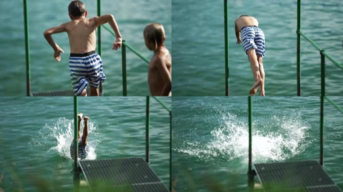 小男孩潜入水中。十几岁的孩子在码头码头以超慢动作坠入湖中。孩子们在暑假期间玩得开心