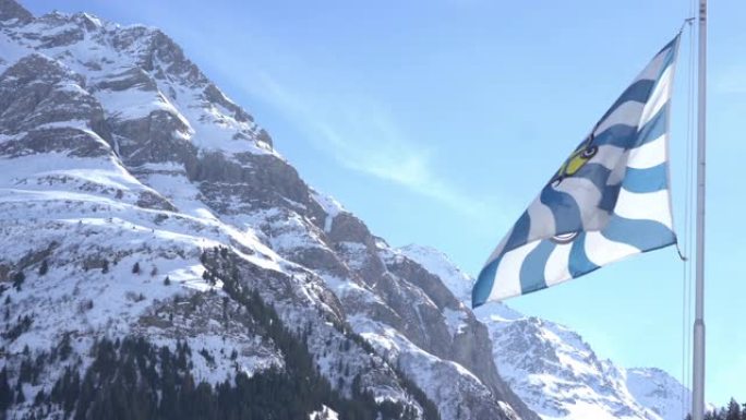 瑞士Grisons Canton旗飘扬，背景是白雪皑皑的山脉
