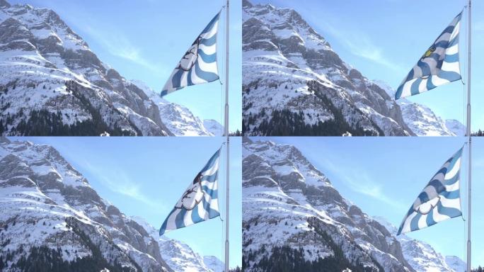 瑞士Grisons Canton旗飘扬，背景是白雪皑皑的山脉