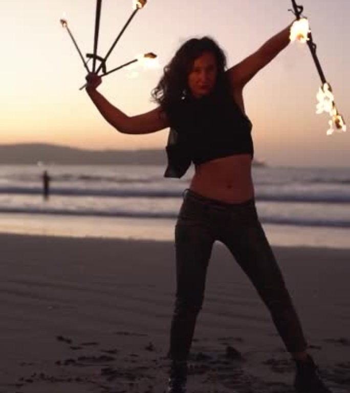 拉丁年轻女子晚上在海滩上用火表演