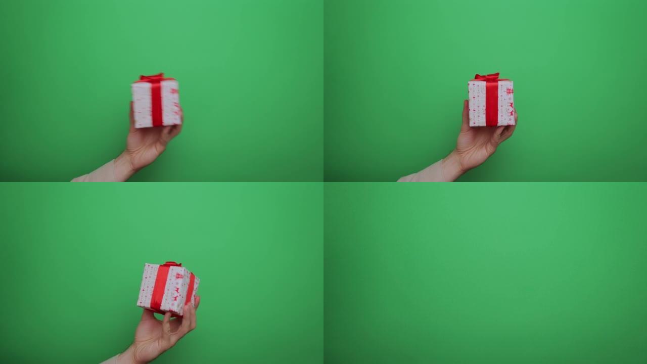 特写男人的手握着一个红色的礼品盒在他的手掌中颤抖，并在绿色屏幕色度键的背景下降低。赠送礼物或惊喜。庆