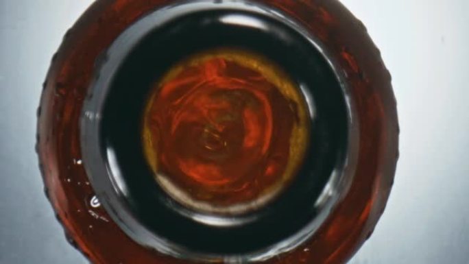 金色ipa飞溅烧瓶顶视图。瓶子里冒泡的特写不起泡液体