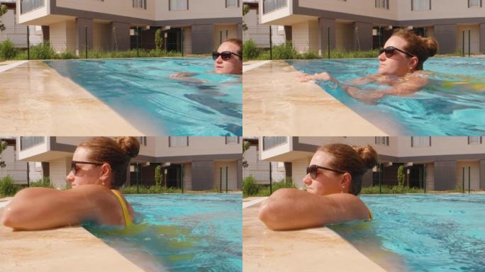 游泳池里一个戴着墨镜的女孩游到边缘，看着太阳。慢动作