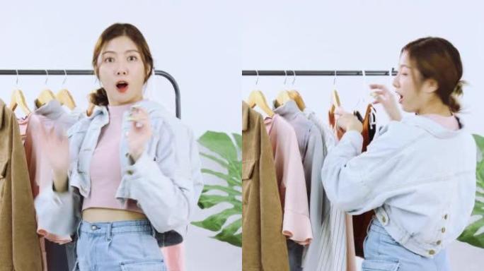 直播。年轻的亚洲女性直播的4k视频显示了智能手机摄像头前的衣服，在家里的白色背景上销售。垂直故事的视
