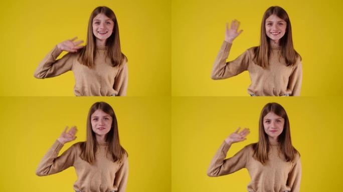 一个女孩在黄色背景上挥手打招呼的4k视频。
