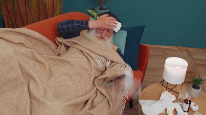 生病的老人患感冒或过敏躺在家里的沙发上打喷嚏擦拭鼻涕成餐巾
