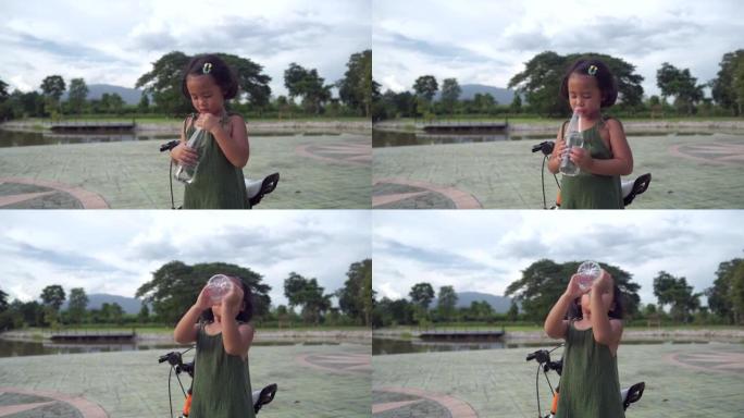 可爱的东南亚小女孩用瓶子喝水