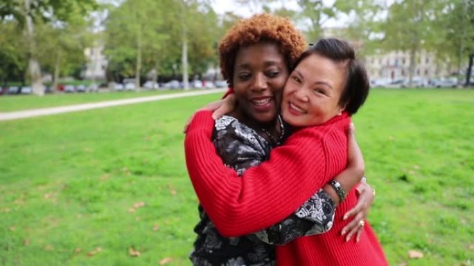 两个女性朋友在公园里互相拥抱，是幸福，多样性和团结的概念。