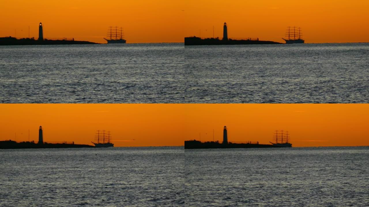 高大的船在日落时海中灯塔的背景下